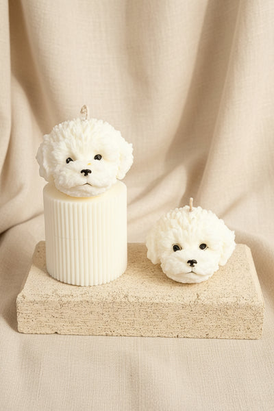 Two white ceramic dog figurines on a beige stand against a brown fabric background
