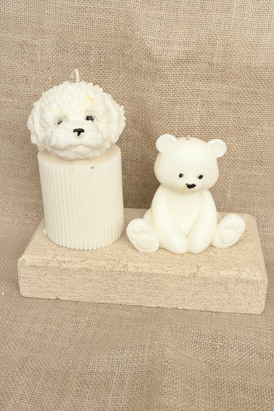Two small white figurines of a dog and a bear on a textured brown background