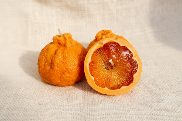 Two orange peel candles on a burlap background