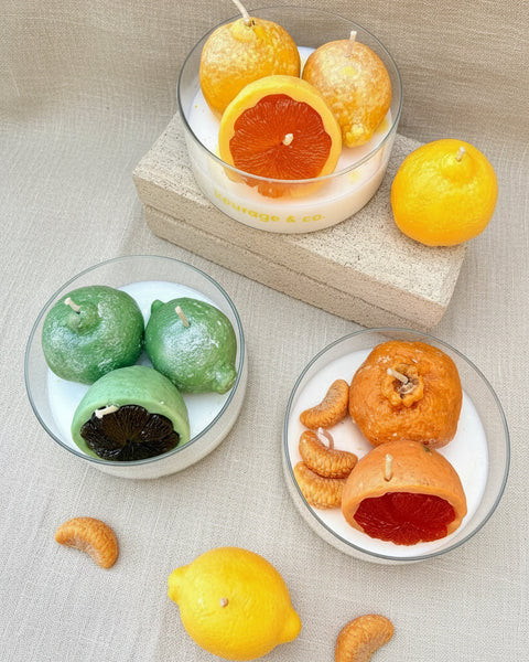 Decorative candles shaped like fruits on a textured surface