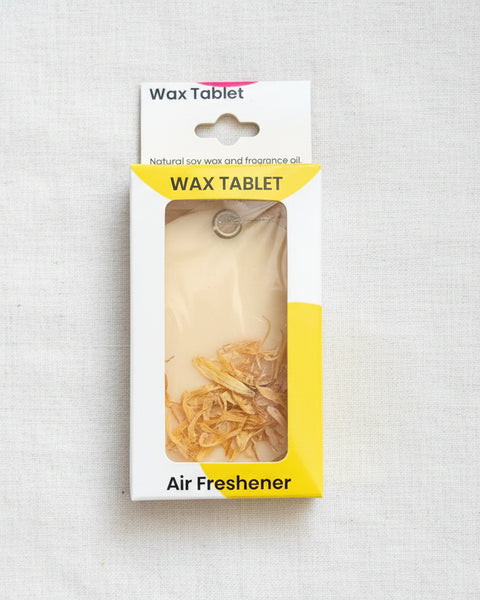 Wax tablet air freshener in packaging on a textured brown background