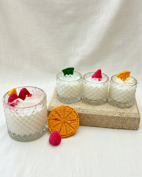 Four small glass cups with decorative elements on a textured surface