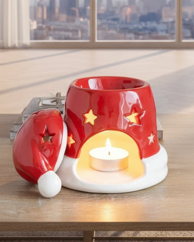 Red and white ceramic candle holder with Santa hat design on a wooden surface.