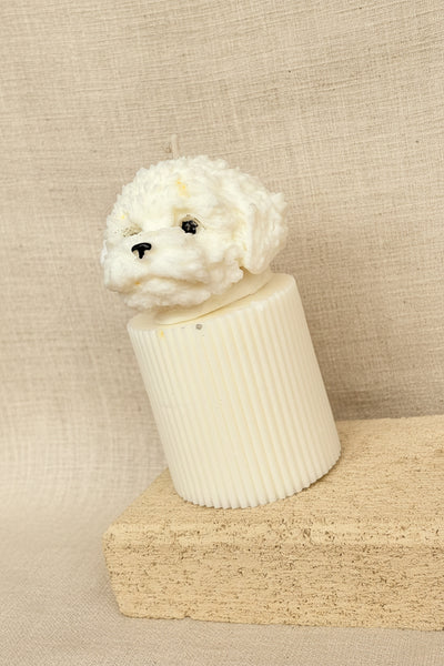 Candle shaped like a dog's head on a textured surface with a burlap background