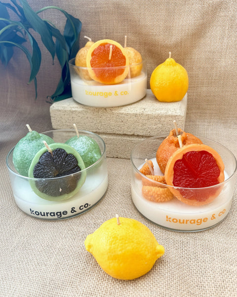 Fruit-shaped candles on a textured surface with 'kourage & co.' branding.