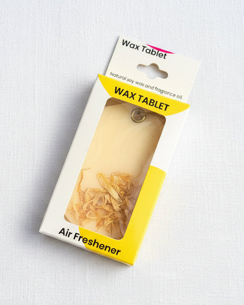 Wax tablet air freshener in packaging on a textured brown background