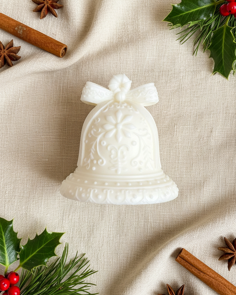 A small white decorative bell-shaped candle with a bow on top, placed on a textured tan burlap fabric background.