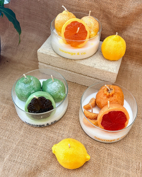 Decorative candles shaped like fruits on a textured surface