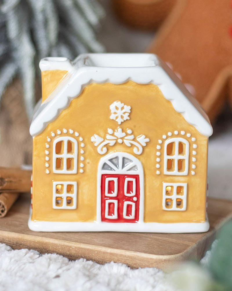 Decorative gingerbread house on a wooden board with a star and cinnamon stick in the background.