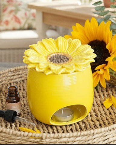 Yellow sunflower-shaped diffuser on a woven surface with a sunflower in the background
